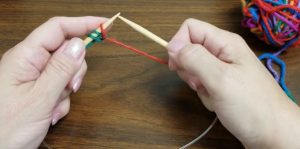 Hands demonstrating a knitting technique during an A String Thing class